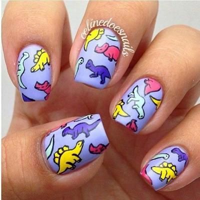 Chica con un diseño de uñas de dinosaurios en diferentes colores