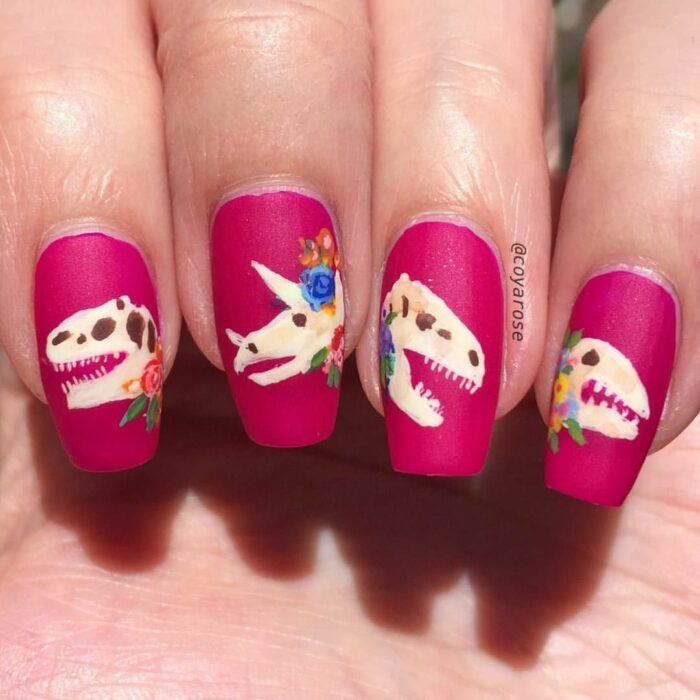 Chica con un diseño de uñas de dinosaurios en diferentes colores