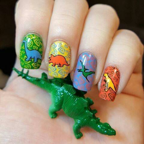 Chica con un diseño de uñas de dinosaurios en diferentes colores