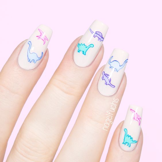 Chica con un diseño de uñas de dinosaurios en diferentes colores