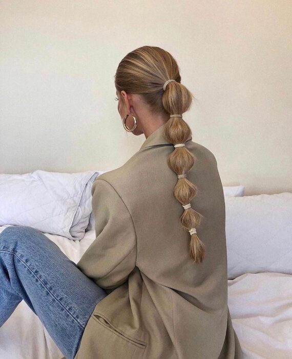 Chica con una coleta baja sujetada en forma de burbujas