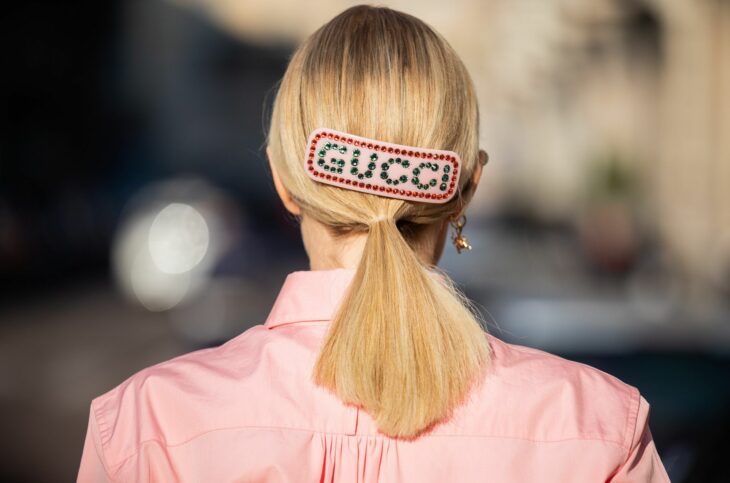Chica con una coleta baja sujeta con un broche que dice Gucci