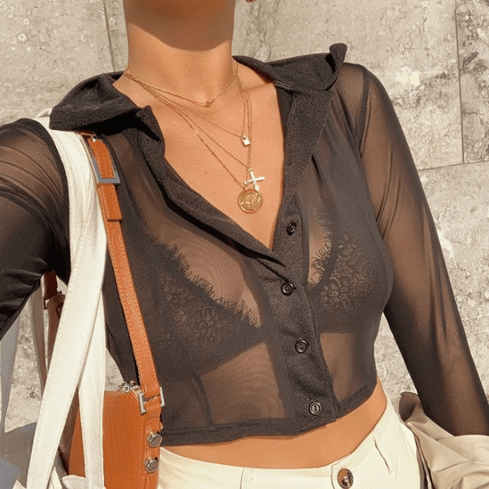 blusa negra transparente, bralette negro de encaje, pantalones blancos, bolso café de cuero