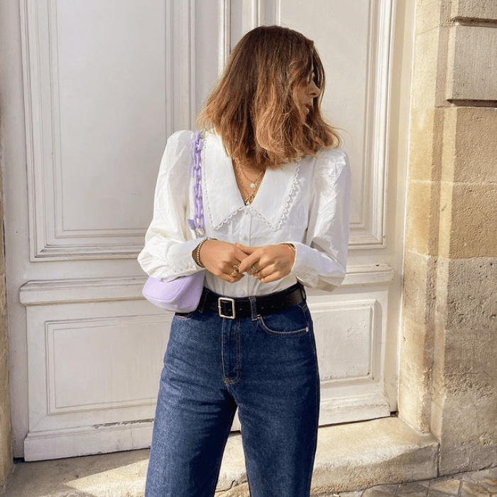 chica de cabello claro usando una blusa blanca con cuello bobo, jeans a la cintura