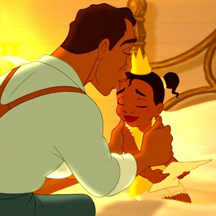 Escena de la película Tiana y el sapo. Tiana sentada en la cama y su papá leyendo un cuento