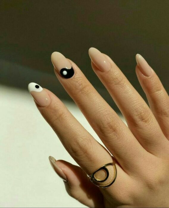 Chica mostrando sus uñas con diseño Yin Yang en color blanco, nude y negro