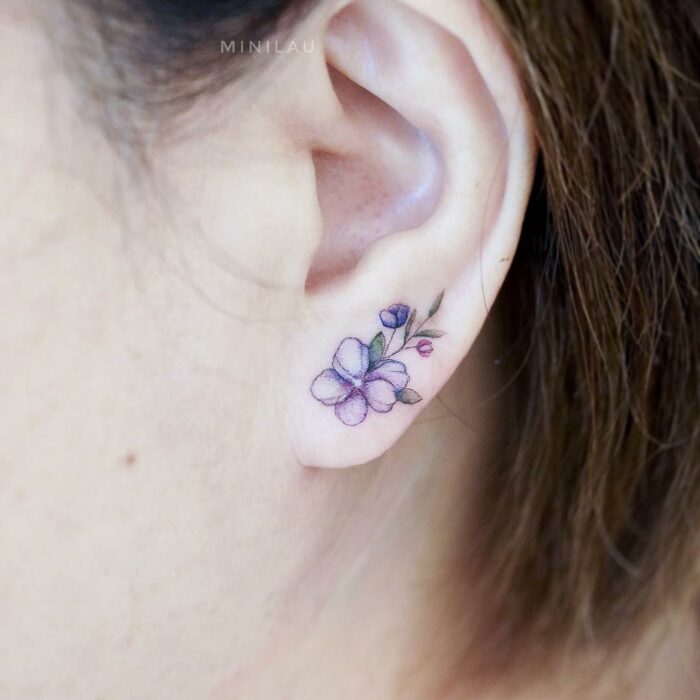 Chica con un tatuaje en la oreja en forma de flor en el lóbulo