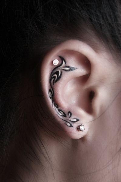 Chica con un tatuaje en la oreja en forma de olas en blanco y negro
