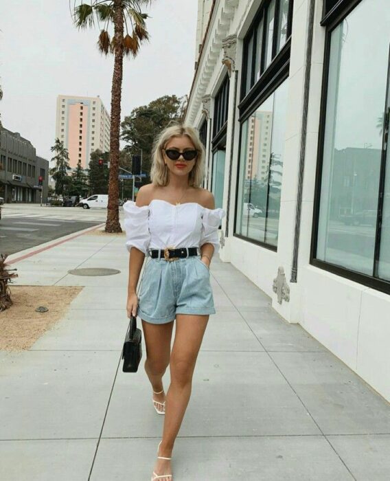 Chica usando unos mom shorts con blusa hasta los hombros y sandalias