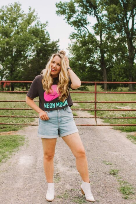 Chica usando unos mom shorts con camiseta estampada y botas vaqueras