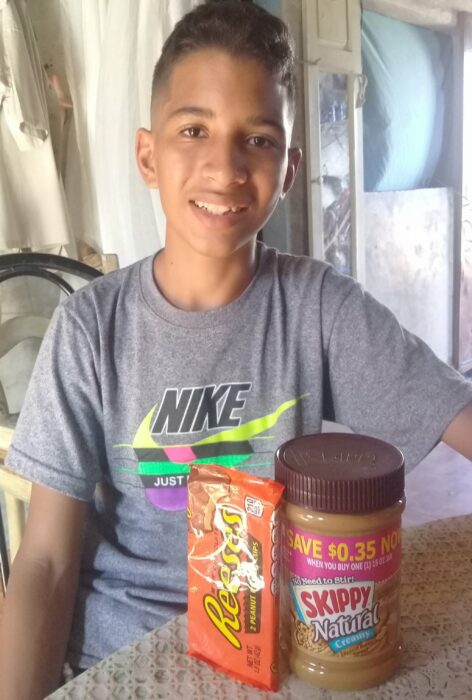 Niño Samuel Mendoza posando para una fotografía mientras come mantequilla de maní