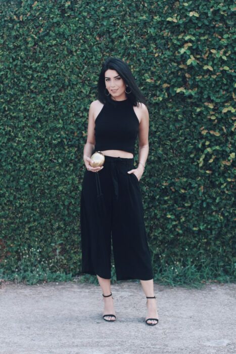 Chica con un top negro y pantalones culottes con sandalias