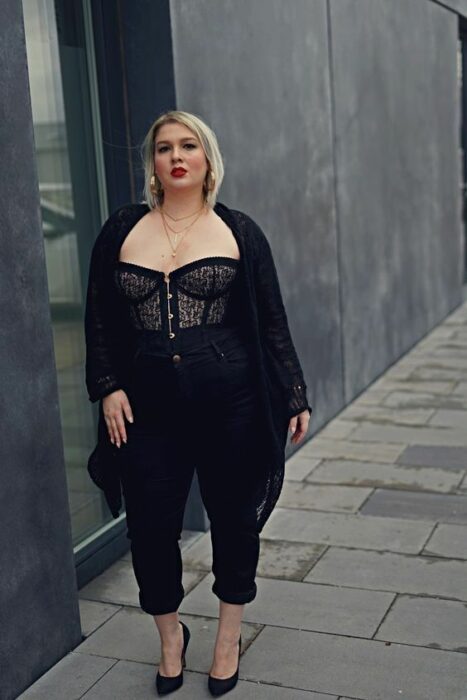 Chica con outfit negro y suéter sobre un top de encaje