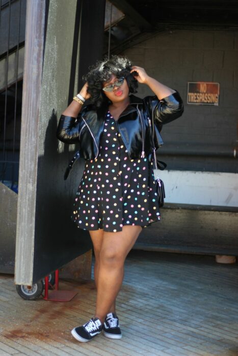 Chica con vestido negro, chaqueta de cuero y tenis