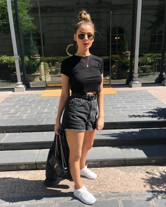 Chica con pantalones cortos, tenis blancos y camiseta negra