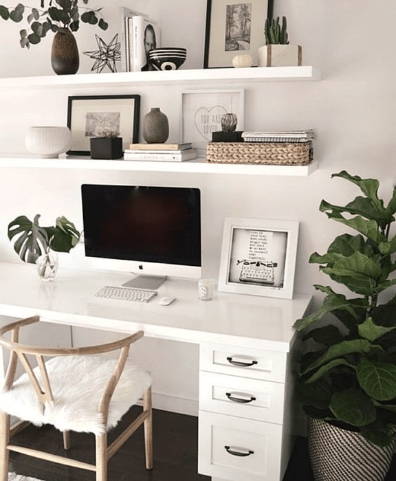 oficina blanca, minimalista, monocromática con escritorio y estanterías blancas, silla metálica, computadora y macetas