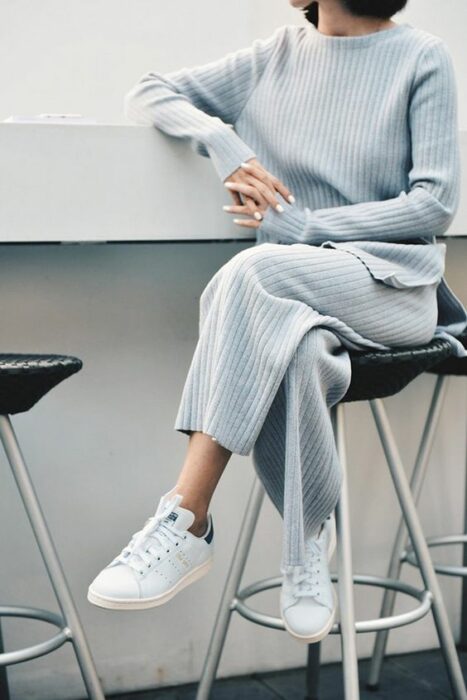 Chica usando conjunto de chándal color azul grisáceo y tenis blancos