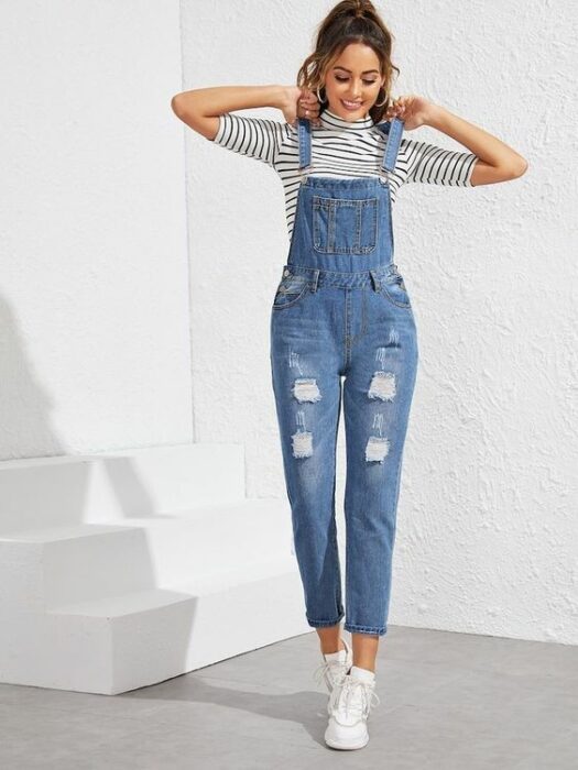 Chica usando overol de mezclilla y tenis blancos y blusa blanca con rayas azules