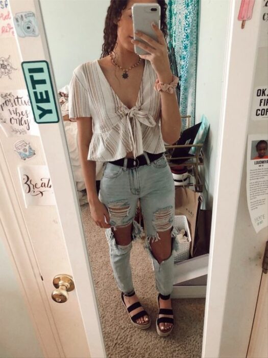 Chica usando blusa holgada clara, con mom jeans rotos y sandalias negras
