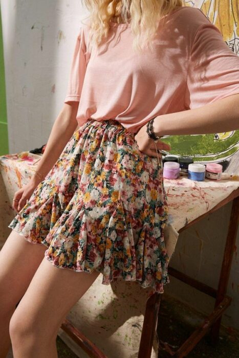 Chica usando blusa rosa de manga corta y falda corta con estampado de flores