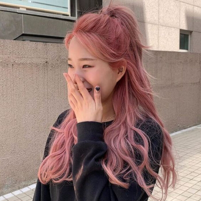 Chica de cabello largo ondulado y recogido en media cola y con tinte 'Gold Pink Hair'