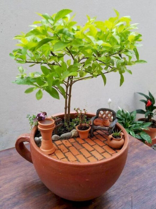 Mini jardín en taza de color ladrillo con una pequeña terraza