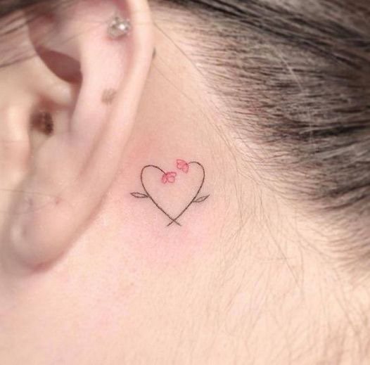 Chica con un tatuaje detrás de la oreja con un corazón y flores 