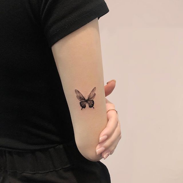 Chica mostrando un tatuaje de mariposa en el codo en tono negro; 15 Bellos tatuajes con mariposas para iniciar una metamorfosis