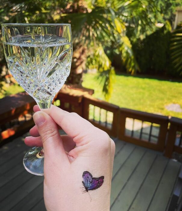 Minitatuaje de mariposa en la mano en tonos morado y rosa; 15 Bellos tatuajes con mariposas para iniciar una metamorfosis