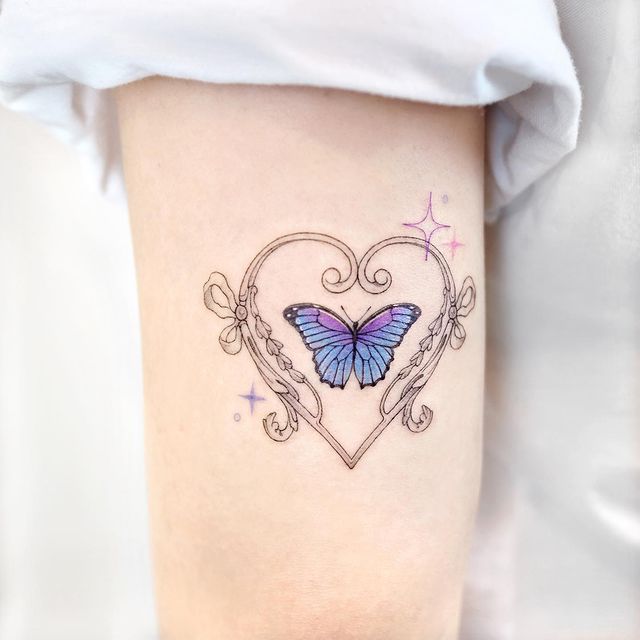 Tatuaje de mariposa en tonos morados rodeado por un corazón; 15 Bellos tatuajes con mariposas para iniciar una metamorfosis