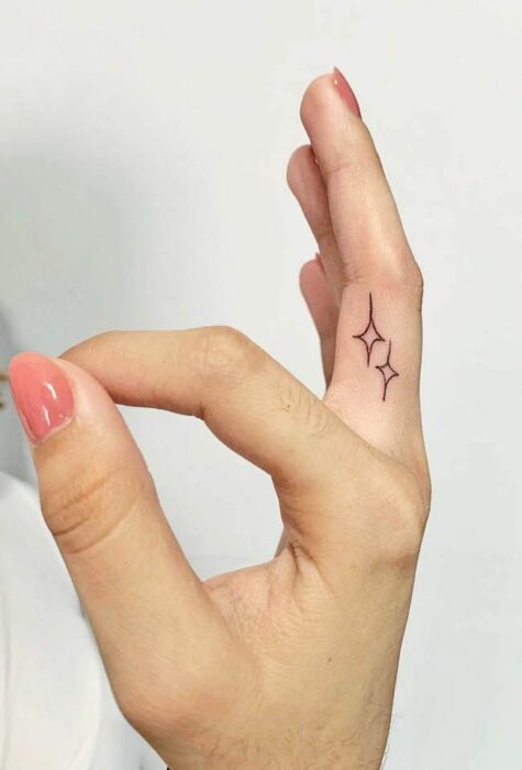 Chica con un tatuaje en forma de estrellas en el dedo medio