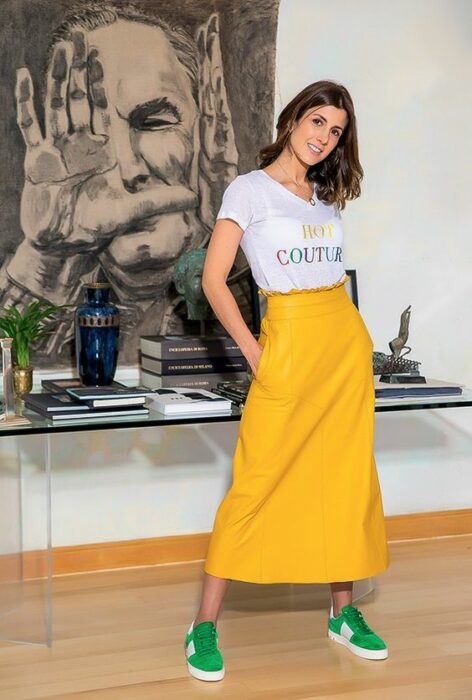 Mujer llevando falda larga en tono amarillo mostaza con tenis verdes; 13 Outfits con tenis neón para deslumbrar a cada paso