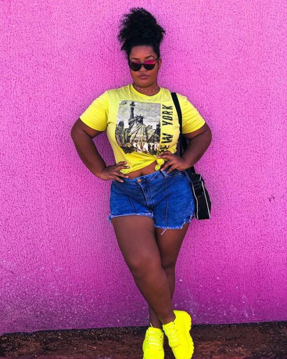 Chica con short de mezclilla y top amarillo neón; 13 Outfits con tenis neón para deslumbrar a cada paso