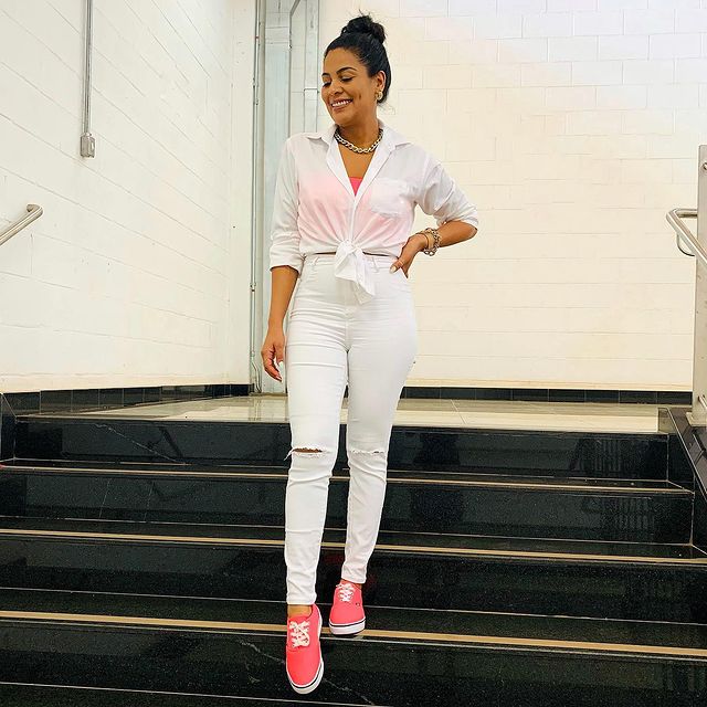 Mujer con outfit en tono blanco de dos piezas y tenis en contraste naranja neón; 13 Outfits con tenis neón para deslumbrar a cada paso