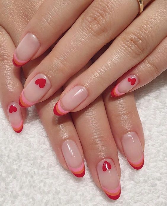 Manicura con estilo francés en tonos rojos y rosas decorada con corazones; Ideas para manicura aesthetic