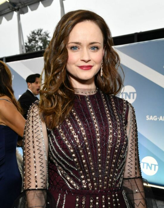 Alexis Bledel usando un vestido negro de manga larga con transparencias y el cabello suelto