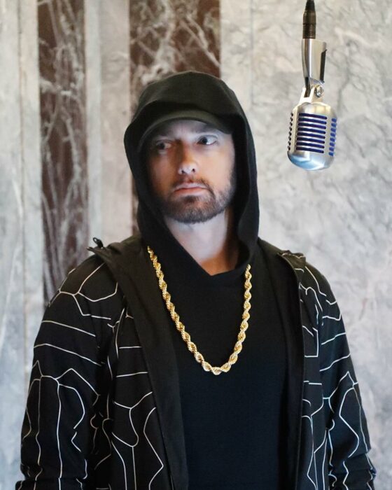 Eminem usando una camiseta negra, sudadera con detalles grises y una cadena dorada