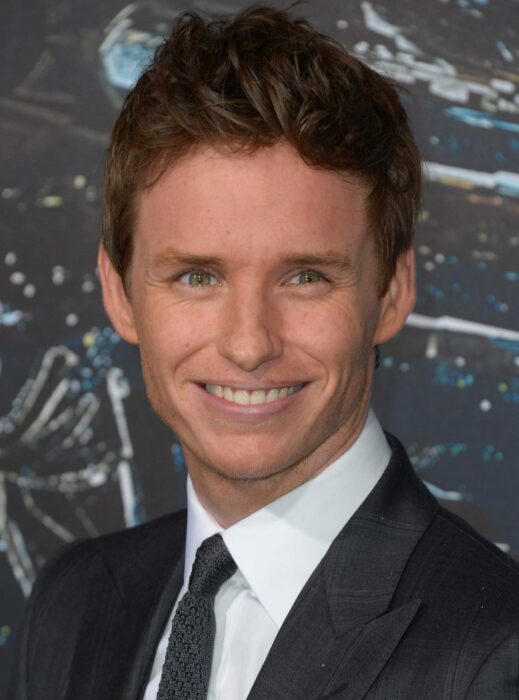 Eddie Redmayne sonriendo y usando un traje elegante