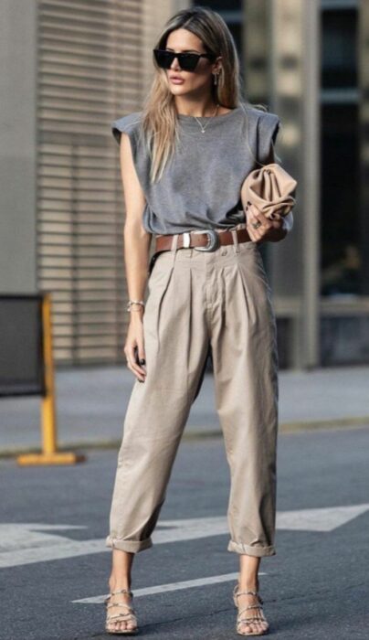 Chica en pantalones cafés, blusa gris y tacones