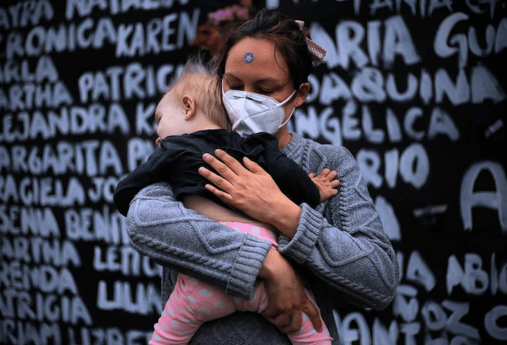 Mujer sosteniendo a su bebé en brazos mientras está en la marcha de 8 marzo 2021