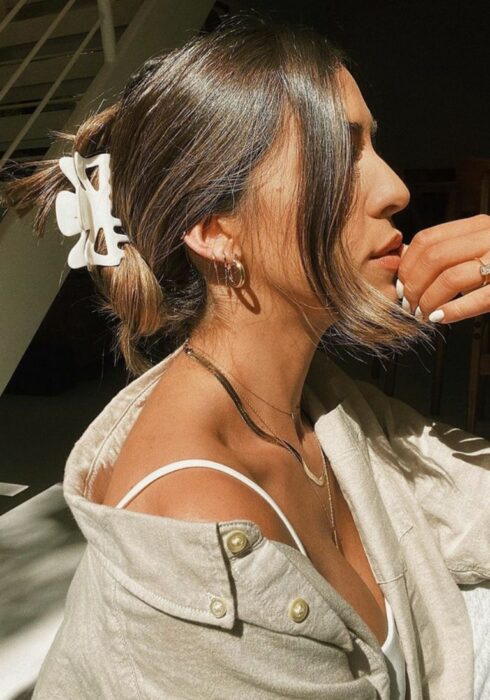 Chica usando una pinza para sujetar su cabello