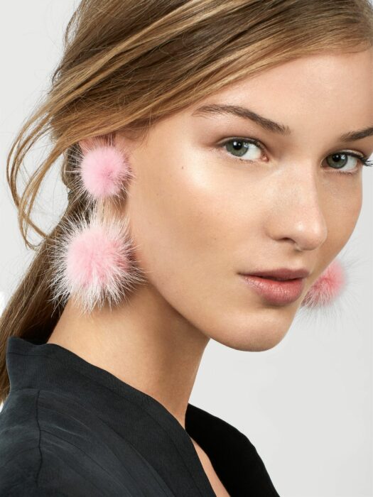 Chica usando pompones como aretes
