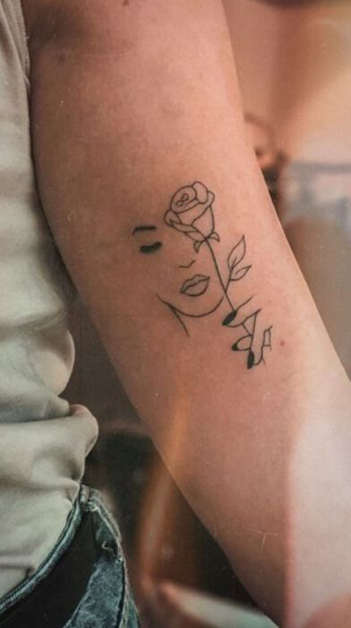 Tatuaje de rostro y rosa en el interior del antebrazo
