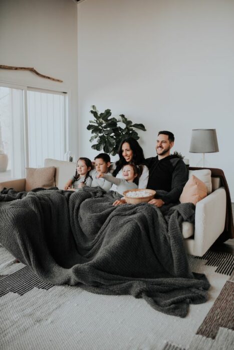 Familia recostada en la cama viendo películas