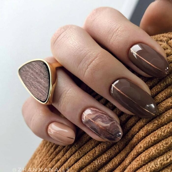 Manicura en tono café con efecto mármol sobre tono beige
