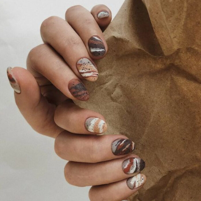 Manicura con tonos café y diseño de líneas