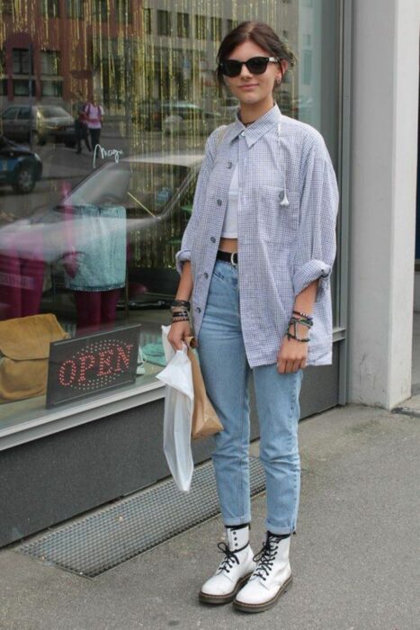 Chica usando jeans, botas Dr. Martens y una blusa larga azul
