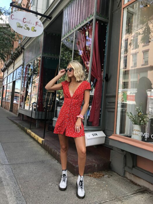 Chica usando un vestido blanco con puntos y botas Dr. Martens blancas con cintas negras mientras posa para una foto
