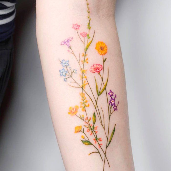 Tatuaje de flores mostrando el crecimiento de diferentes plantas sobre el antebrazo