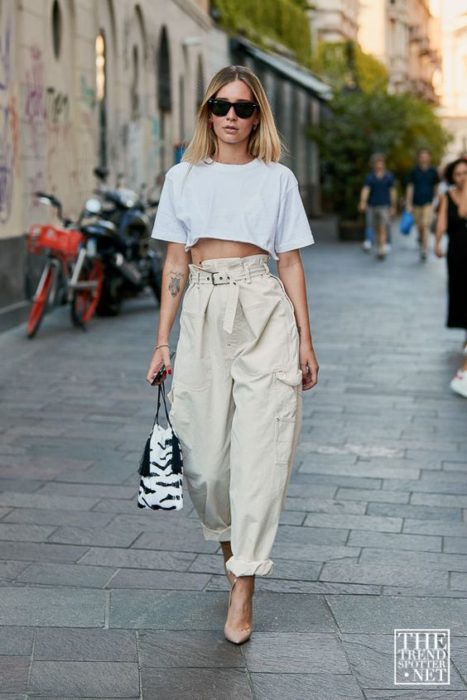 chica rubia con lentes de sol, crop top blanco, jeans slouchy paperbag, bolsa de mano y tacones nude
